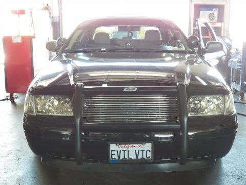 2003 Ford Crown Victoria - Close front view of a black sedan showing billet grille, brush guard and EVIL VIC California plate.