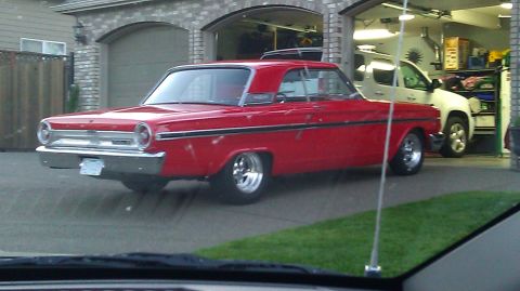 1964 Ford Fairlane - Red 1964 Ford Fairlane with chrome wheels parked outside a garage with a white SUV inside.
