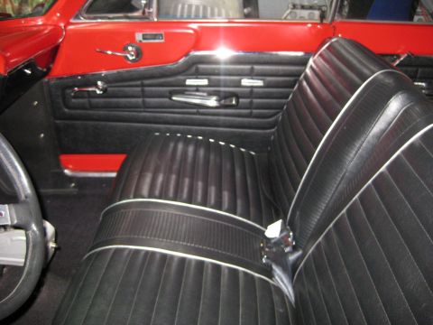1964 Ford Fairlane - The interior of a 1964 Ford Fairlane shows black vinyl seats with white piping and red door panels.
