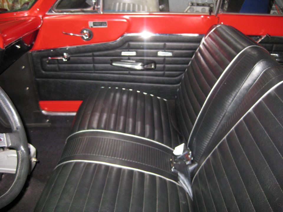 1964 Ford Fairlane interior with black pleated seats and red door panels