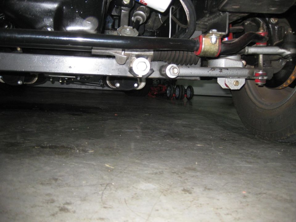 Underside view of rack-and-pinion steering conversion with red poly bushings and sway bar