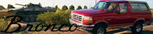 2012 Ford Bronco - A red Ford Bronco is parked next to a military tank in an outdoor setting.