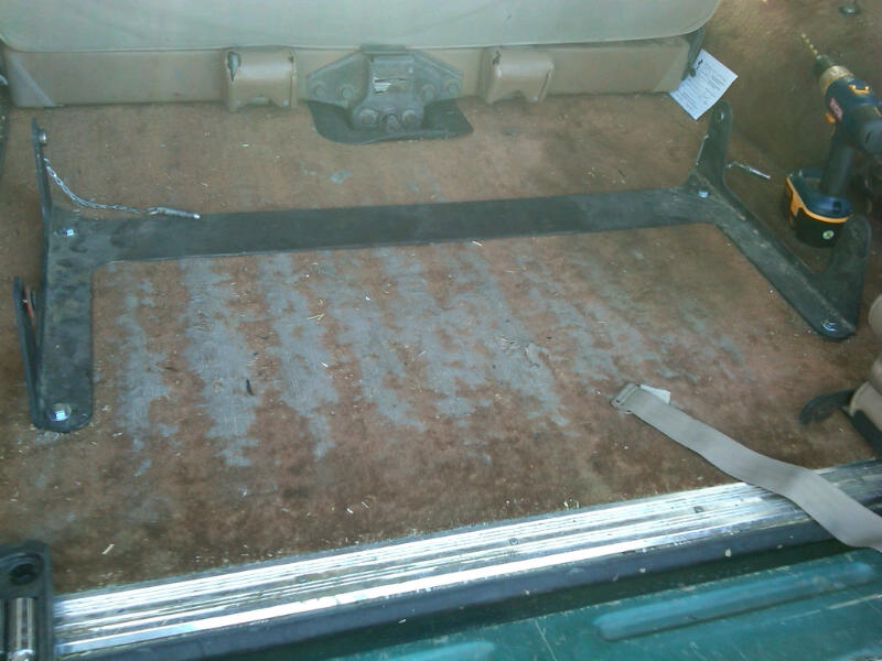 Vehicle interior floor with rear seat frame brackets removed and exposed carpet