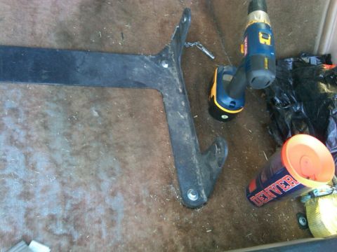 1987 Ford Bronco - Metal bracket and tools are on the carpeted floor of a vehicle's interior.