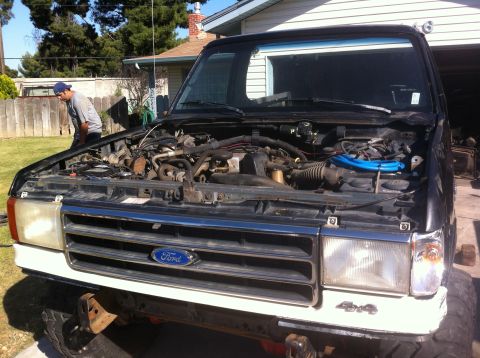 1989 Ford Bronco - Front view of a black Ford truck with its hood open, revealing the engine compartment and a "4x4" emblem.