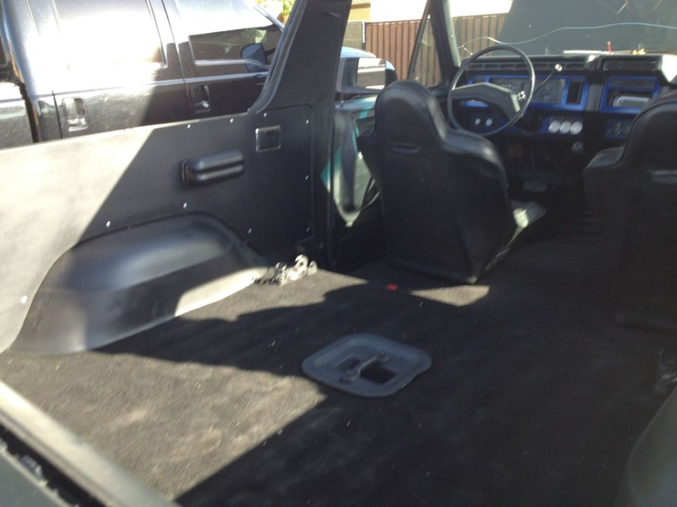 Interior view of a Ford Bronco, showing the dashboard, seats, and cargo area. Another vehicle is visible outside