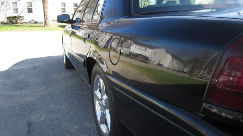 2003 Mercury Marauder - A black sedan is parked on a paved surface, with houses reflected in its shiny paint.