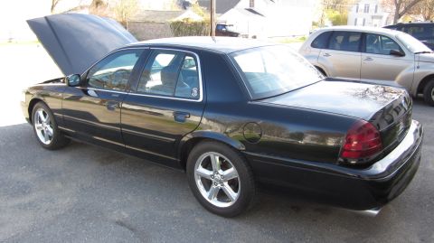 2003 Mercury Marauder - A black 2003 Mercury Marauder is parked outside with its hood up, next to another vehicle.
