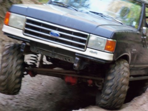 1968 Ford Bronco - This Ford truck, likely from the late 1980s or early 1990s, navigates a challenging off-road terrain.