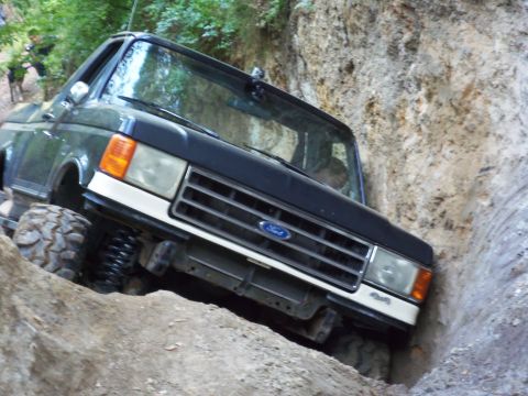 1968 Ford Bronco - Ford Bronco is shown off-roading on a steep dirt trail.