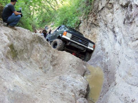 1968 Ford Bronco - A Ford Bronco II navigates a challenging off-road trail, with spectators observing the difficult descent.