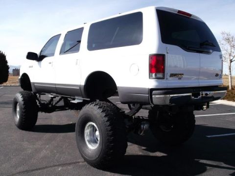 2001 Ford Excursion - This white 2001 Ford Excursion is heavily modified with a lifted suspension and massive off-road tires, giving it an imposing stance.