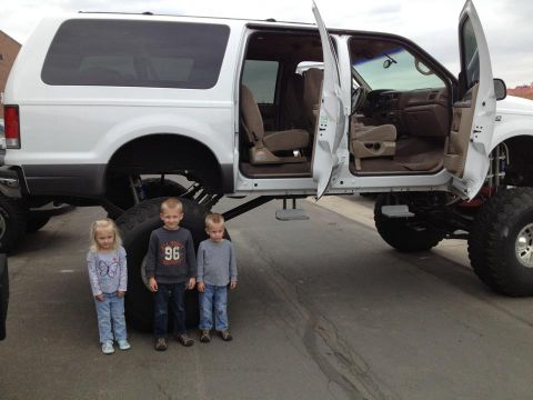 2001 Ford Excursion - Modified 2001 Ford Excursion with custom lift and large tires, seen with three children.