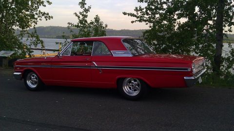 1964 Ford Fairlane - Side view of a red 1964 Ford Fairlane parked next to a body of water.
