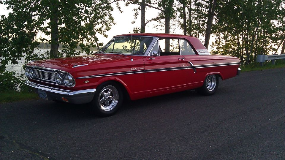 Red Ford Fairlane 500 hardtop on chrome mags parked by a river at sunset