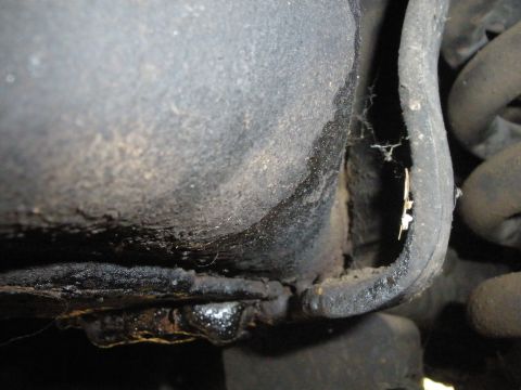 1988 Ford F-250 - A close-up view of the underside of a vehicle, focusing on frame and suspension components with visible grease and rust.