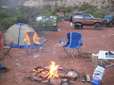 1986 Ford Bronco II - A brown 1987 Ford Bronco II is parked at a campsite in a desert landscape, with tents and a campfire in the foreground.