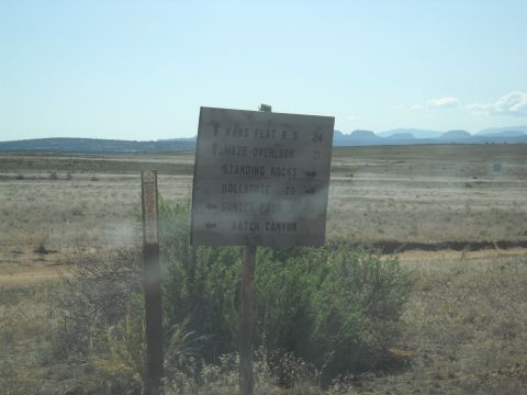 1986 Ford Bronco II - A directional signpost stands in a dry, grassy landscape under a clear blue sky.