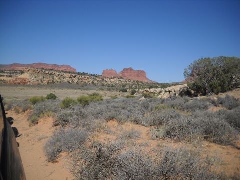 1986 Ford Bronco II - A view of the desert terrain with distant red rock formations under a bright blue sky.