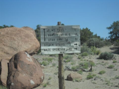 1986 Ford Bronco II - A weathered signpost directs travelers to various desert destinations under a clear blue sky.