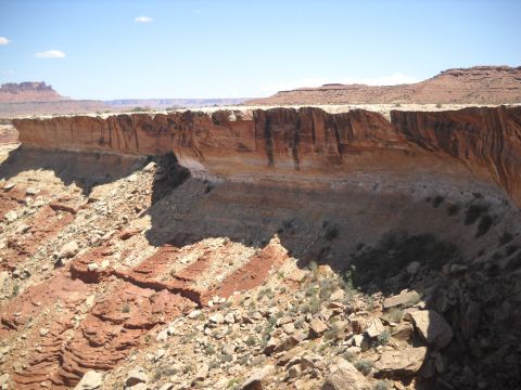1986 Ford Bronco II - A vast desert scene unfolds with dramatic layered cliffs and distant mesas under a clear blue sky.