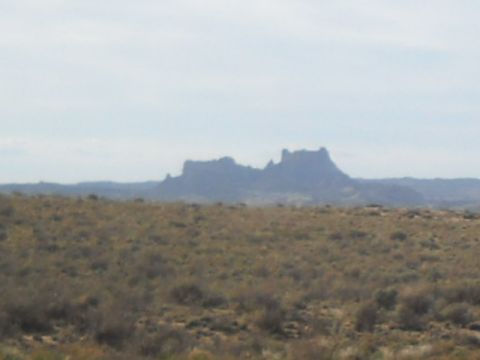 1986 Ford Bronco II - The photo shows a wide desert scene with prominent rock formations on the horizon.