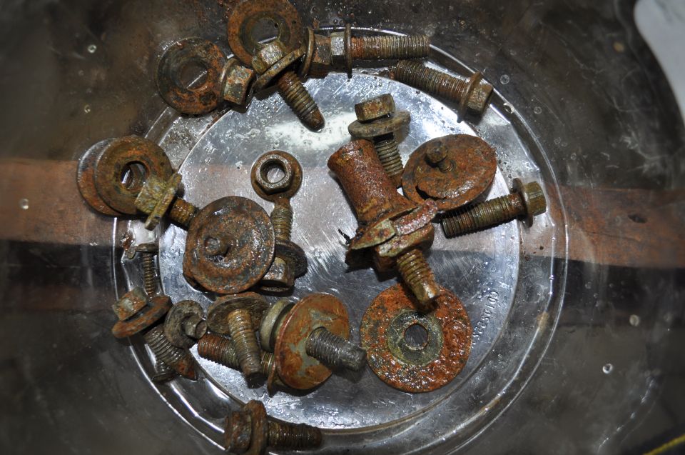 Pile of rusty bolts and washers in a clear container