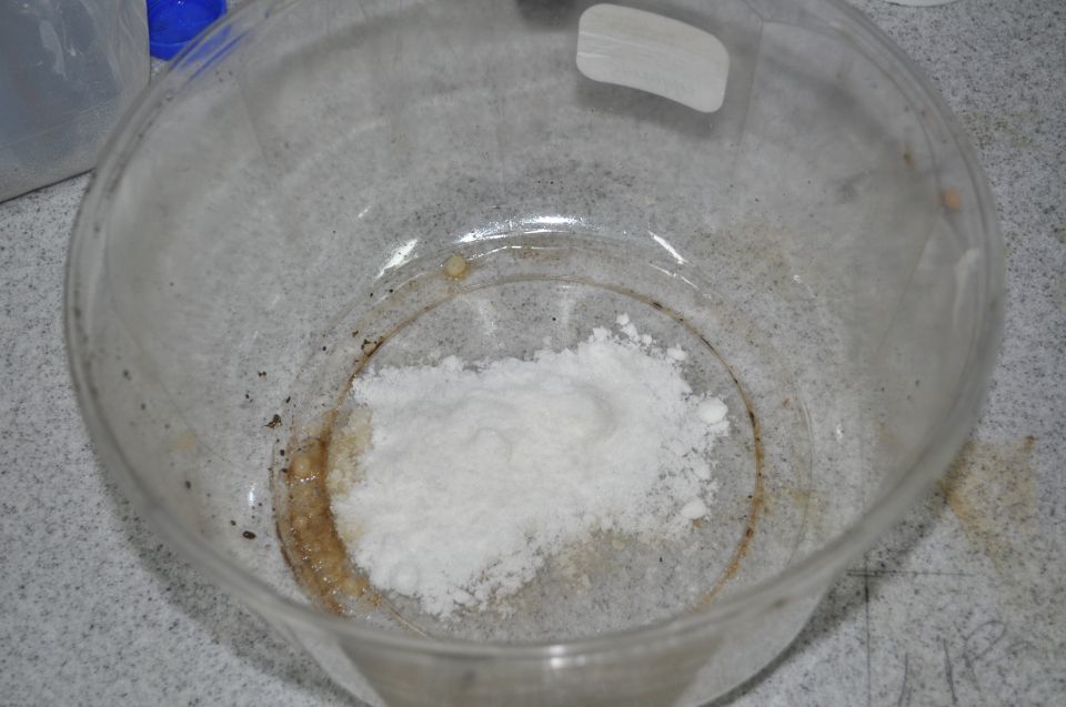 White powder in a clear glass dish with some brown residue around the edges