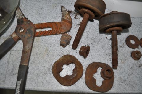 1986 Ford Bronco - A collection of heavily rusted automotive parts and tools are laid out on a workbench.