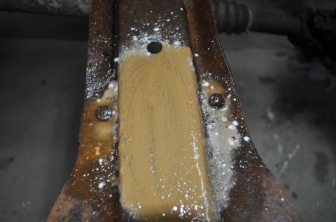1986 Ford Bronco - A close-up shot shows a heavily rusted metal component undergoing a cleaning process.