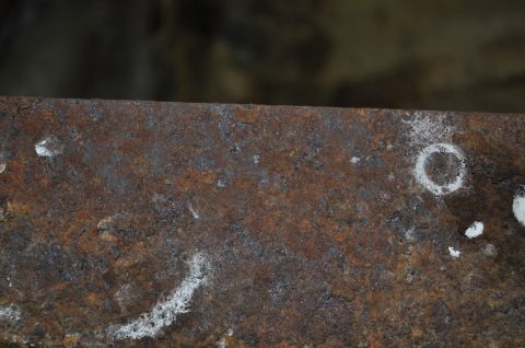 1986 Ford Bronco - This image shows a heavily corroded metal surface, likely a vehicle part, with visible rust and some white markings.