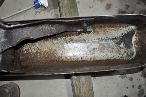 1986 Ford Bronco - A heavily rusted metal component, possibly from a vehicle's undercarriage, shows significant wear and a crack.