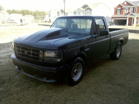 1992 Ford Bronco - This black pickup truck features a prominent aftermarket hood and custom wheels.