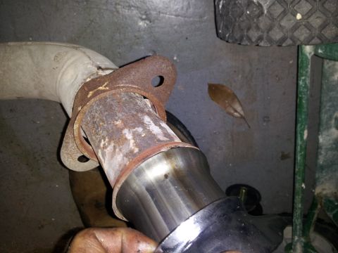 1995 Ford Bronco - This photo shows a close-up of a vehicle's exhaust pipe connection, with a rusty flange and a shiny new pipe section.