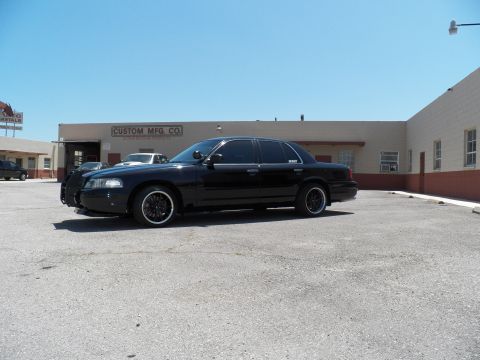 2003 Ford Crown Victoria - Front quarter view of a black sedan fitted with a push-bar grille guard in an industrial lot.