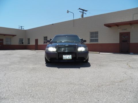 2003 Ford Crown Victoria - Black sedan shot straight-on with headlights lit and an EVIL VIC California plate.
