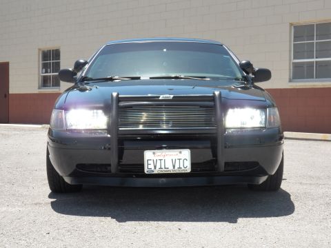 2003 Ford Crown Victoria - Tight front view of a black Crown Victoria showing the EVIL VIC plate and grille guard.