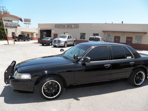 2003 Ford Crown Victoria - Driver-side profile of a lowered black Crown Victoria parked before a Custom Mfg Co building.