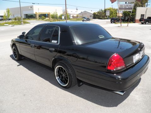 2003 Ford Crown Victoria - Rear driver-side view of a black Crown Victoria with deep-lip wheels and rear diffuser tips.