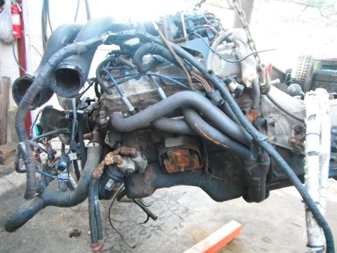 1988 Ford Bronco - This engine assembly is covered in grime and rust, with numerous hoses and wires connected.