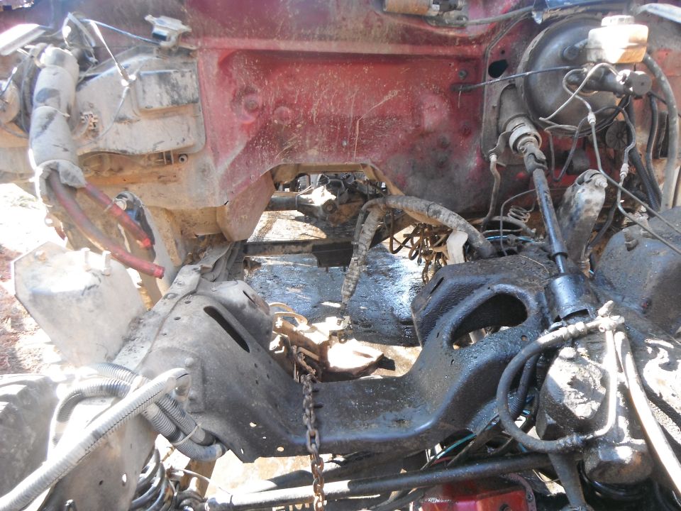 Engine bay of a vehicle, appears to be disassembled or heavily modified. Lots of grime and exposed mechanical parts