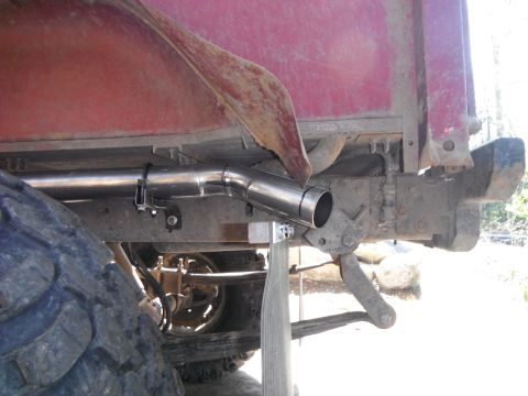 1988 Ford Bronco - A custom exhaust pipe is visible on the rear underside of a red truck, with a large tire in the foreground.