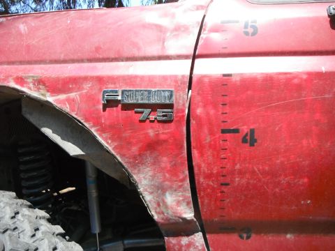 1988 Ford Bronco - Close-up of a red truck's side, showing a 'F-Super Duty 7.5' badge and height markings on the door.