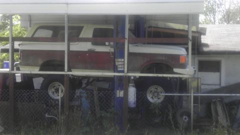 1989 Ford Bronco - 1989 Ford Bronco is parked on a car lift, showing its side profile with a two-tone red and white paint scheme.
