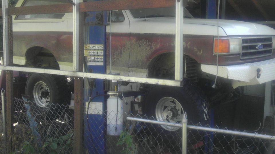 Ford Bronco on a lift, showing front end and side profile. Two-tone paint with maroon and white