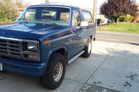 1980 Ford Bronco - A blue Ford Bronco is parked on a concrete driveway in front of a residential house.
