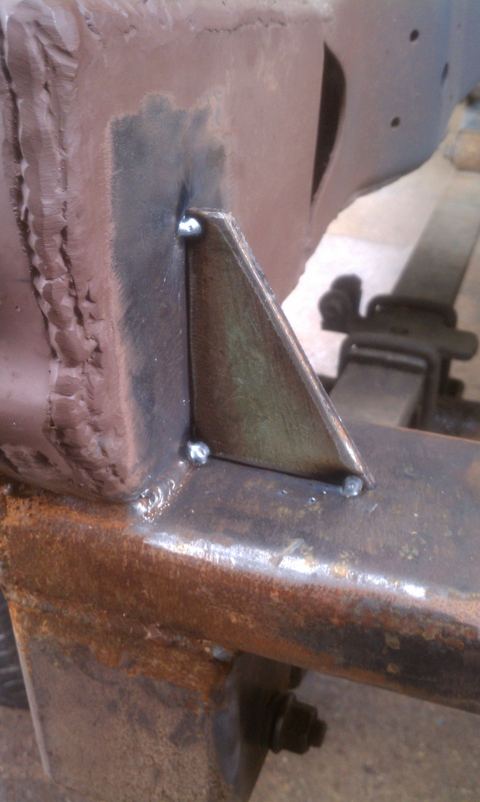 Welded metal bracket on rusty vehicle frame