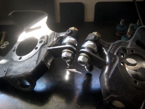 1996 Ford Bronco - Close-up of two automotive steering knuckles and ball joints, likely for a vehicle's suspension system.