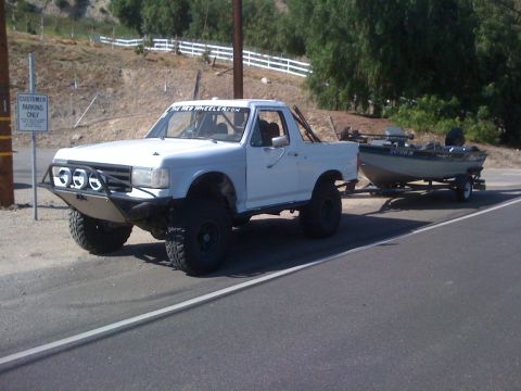 1990 Ford Bronco - Modified 1990 Ford Bronco is seen towing a boat on a trailer on a paved road.