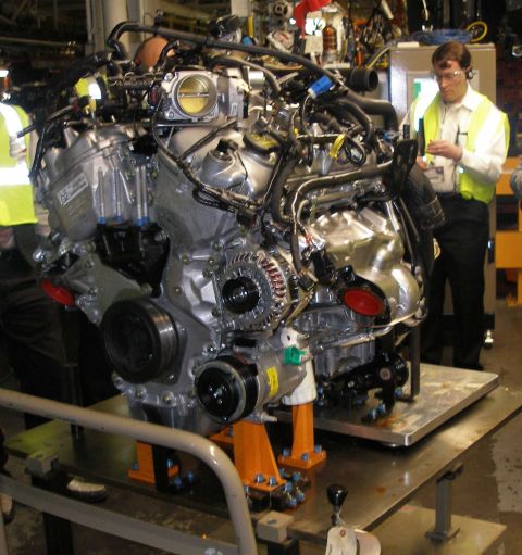 1997 Ford Taurus - Engine assembly displayed on a stand, with workers in the background.
